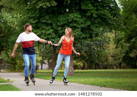Young happy couple roller skating in summer park