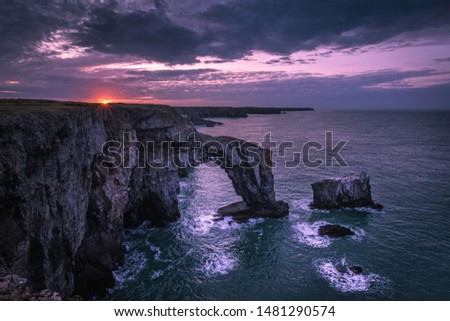 Sunrise over Green Bridge of Wales, famous, natural rock arch, popular landmark and tourists attraction.Colourful sky above dramatic coast of Pembrokeshire,South Wales, UK.Scenic british landscape. Royalty-Free Stock Photo #1481290574