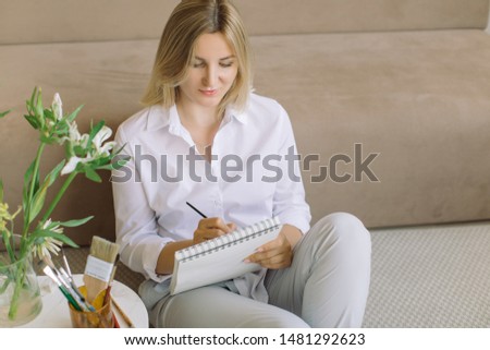 Young professional designer making sketches in stylish Scandinavian nordic interior. Beige colors.