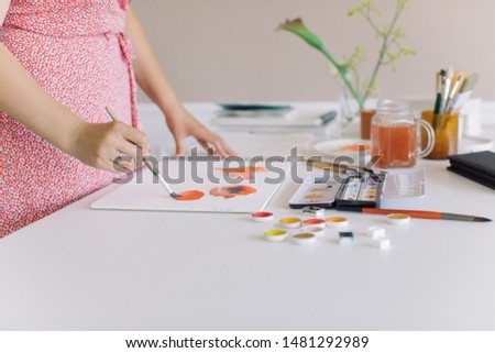 Female making abstract watercolor sketches.  Stylish artistic workspace with professional tools. Copy space.