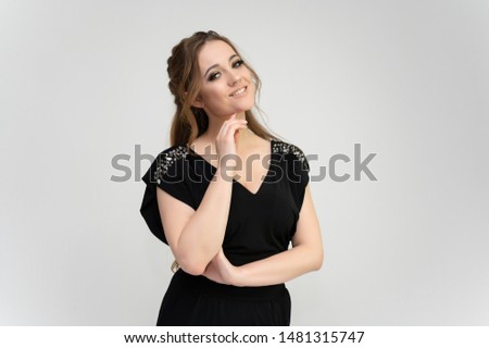 Photo waist-length portrait of a pretty brunette woman girl with long beautiful curly hair on a white background in a black dress. Talking in different poses. Standing facing the camera.