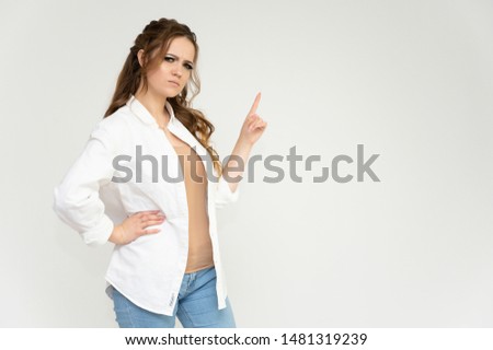 Photo portrait above the knee of a pretty brunette woman girl with long beautiful curly hair on a white background in a white shirt and blue jeans. Talking while standing in front of the camera.