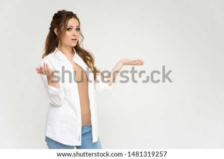 Photo portrait above the knee of a pretty brunette woman girl with long beautiful curly hair on a white background in a white shirt and blue jeans. Talking while standing in front of the camera.