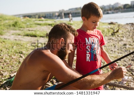 Father and son by the river. A father teaches his son to fish