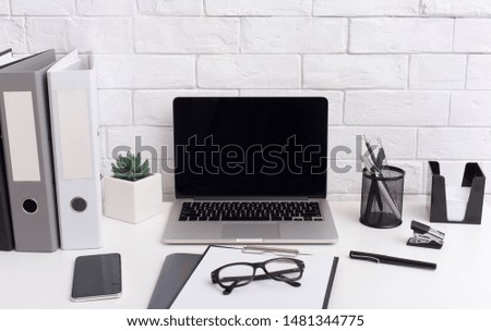 Business workplace. Modern laptop with blank screen and office stationery in black and white style