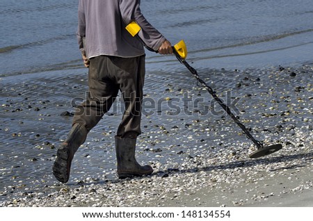 Man using a metal detector swept over the beach. Concept photo of searching or looking for money, gold, job, metals , treasure,  search, hunting, hope. Real people. Copy space