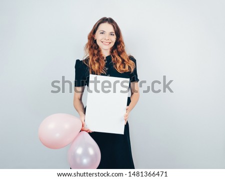 Young woman with mockup poster on gray background. Happy beautiful girl holding a balloons and white canvas  in her hands.
