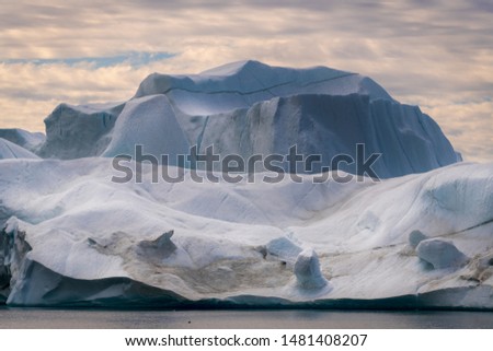 a Greenlandic huge iceberg, the clouds in the sky give the picture a dramatic look