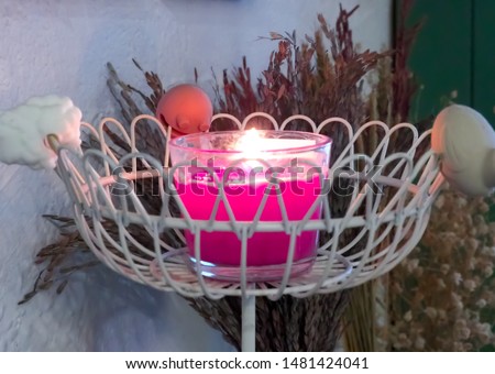 Pink Scented Candle Placed on a steel shelf beside the wall And with dry rice plants Brown on the back of the scented candle floor