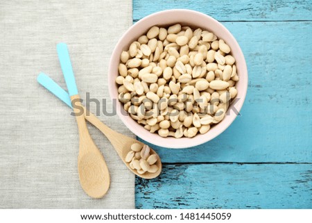 Peanuts in bowl with spoons on blue wooden table