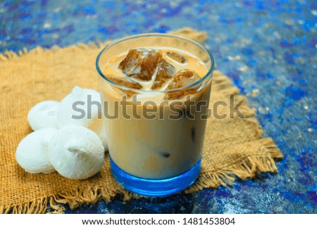 
Ice cubes made of coffee with milk on a blue background. Iced coffee and marsh chalk. Cooling drink. View from above.