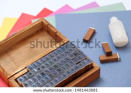 Wooden Alphabet stamps with a color paper and a small bottle of glue. Art background.