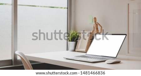 Comfortable workplace with open blank screen laptop and copy space on white desk 