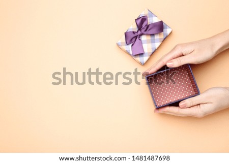Female hands holding gift box on beige background