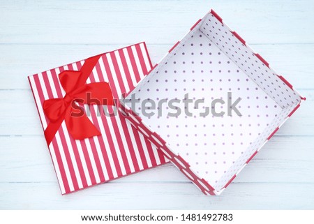 Open gift box with red bow on wooden table