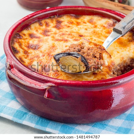 Greek dish moussaka made in a traditional ceramic pot, square format, closeup