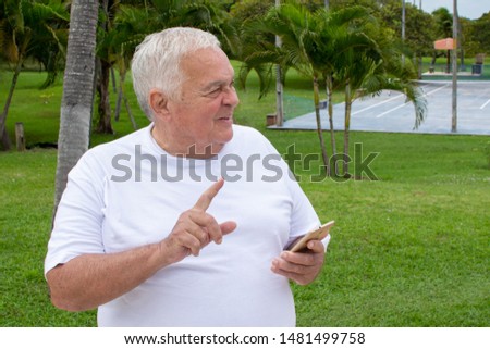 Fat old man searches with cellphone use in nature (mobile phone)