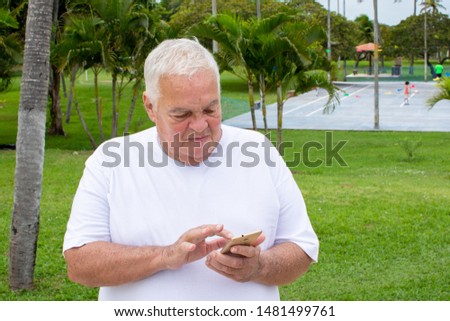 Fat old man searches with cellphone use in nature (mobile phone)