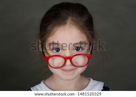 Shooting in the Studio. Portrait of a girl with glasses. The girl is wearing a dress with a white collar.
