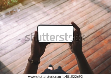 Top view mockup image of a woman holding black mobile phone with blank desktop screen