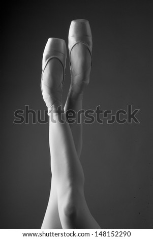 Ballerina in ballet shoe in studio, monochrome