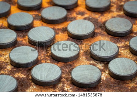 set of small round ceramic ferrite magnets - top view against rusty metal sheet Royalty-Free Stock Photo #1481535878
