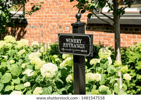 A black winery entrance sign with white lettering outside a building.