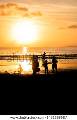 Silhouette of happy family on the beach with sunset landscape view