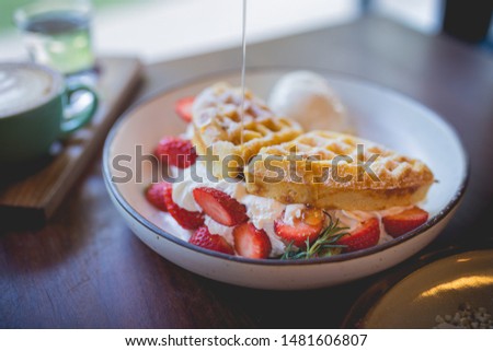Picture of waffle pancake desert with vanilla ice cream, fresh strawberry and honey syrup