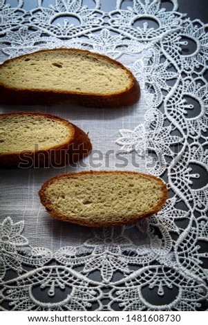 The vertical picture shows a picture of food, fresh bread round, three pieces. Bread lies on a white linen tablecloth