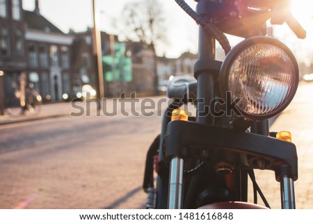 An electric moped on the sidewalk in the city, in the background is a street view with buildings by sunset. Royalty-Free Stock Photo #1481616848