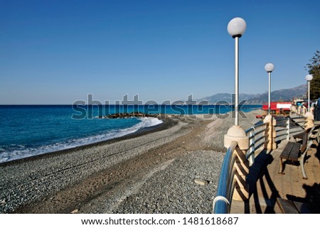 exterior shot of the deserted beach in the morning  on the seaftont in Bordighera with waves and stones