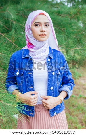Portrait of young muslim woman in white hijab and traditional clothes is making selfie on smartphone sitting on the sofa in modern white interior  side view. 