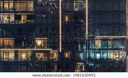 Lights in windows of modern multiple story building in urban setting at night timelapse. Glowing lights in residential skyscraper in Dubai Marina