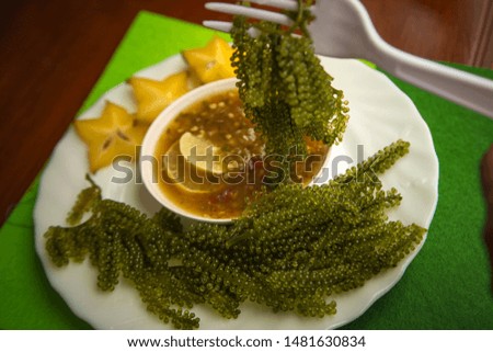 Bunch of seaweed Looks like a bunch of small grains, similar to a bunch of green grapes that are commonly eaten with seafood sauce. 