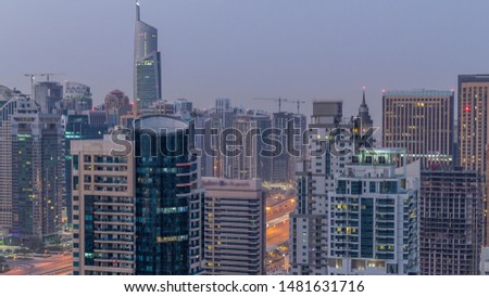 Aerial top view of Dubai Marina and JLT night to day transition timelapse. Skyscrapers before sunrise in Dubai, UAE. Illuminated modern towers and traffic on the road