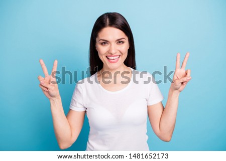 Photo of ecstatic encouraged kind cheerful cute woman showing you double v-sign while isolated with blue background