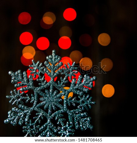  A large snowflake on a  rad and yellow bokeh background of New Year's lights. Christmas texture and background.