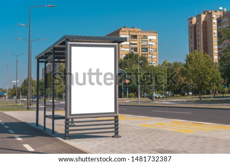 Outdoor advertising poster mock up on bus station in urban surrounding on bright sunny summer day