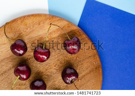 Ripe cherry, top view. On a wooden substrate on a blue background. Geometry. Summer berry. The concept of healthy eating.