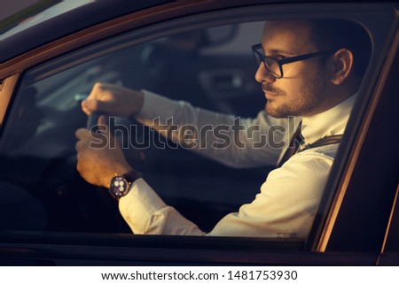 Close up of a businessman driving a car at sunset