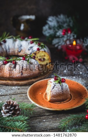 Traditional homemade christmas cake holiday dessert with cranberry and chocolate with new year tree decoration on vintage wooden table background.