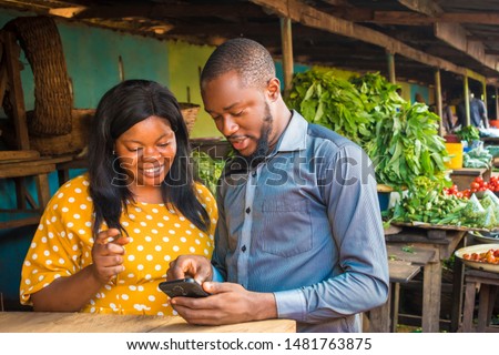 young black business agent meeting with a woman selling in a local market, showing her something on his phone Royalty-Free Stock Photo #1481763875