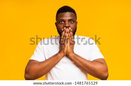 It can't be real. Shocked black guy shut his mouth in amazement, yellow background