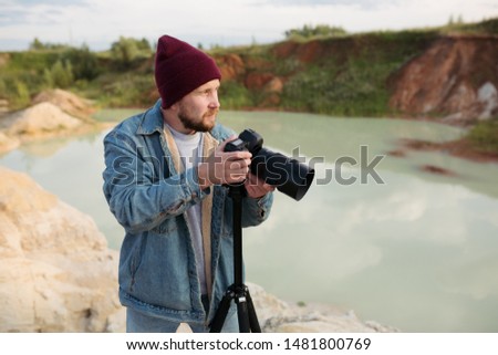 Bearded hipster photographer with a camera in his hands shoots wildlife