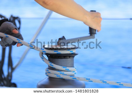 Yachtsman hands dealing with yacht ropes on halyard winch  Royalty-Free Stock Photo #1481801828