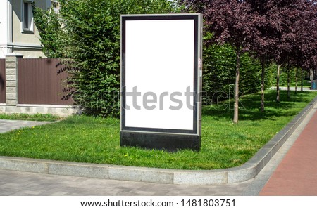 Vertical billboard or citylight mockup template commercial advertisement standing on the grass near trees and a house in a small European cozy town outdoor street sunny summer day, no people