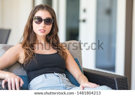 Beautiful woman with vintage sunglasses sitting on a chair