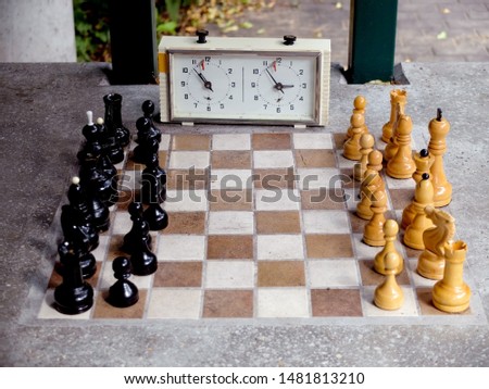 Chess pieces and stopwatch on a board in the park