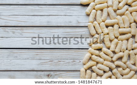 Lots of yellow corn sticks on a white wooden background. Delicious airy dessert. Concept and picture, copy space. Baby food, half.